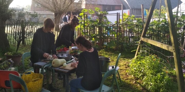 Mensen die in een tuin zitten en groenten aan het snijden zijn.